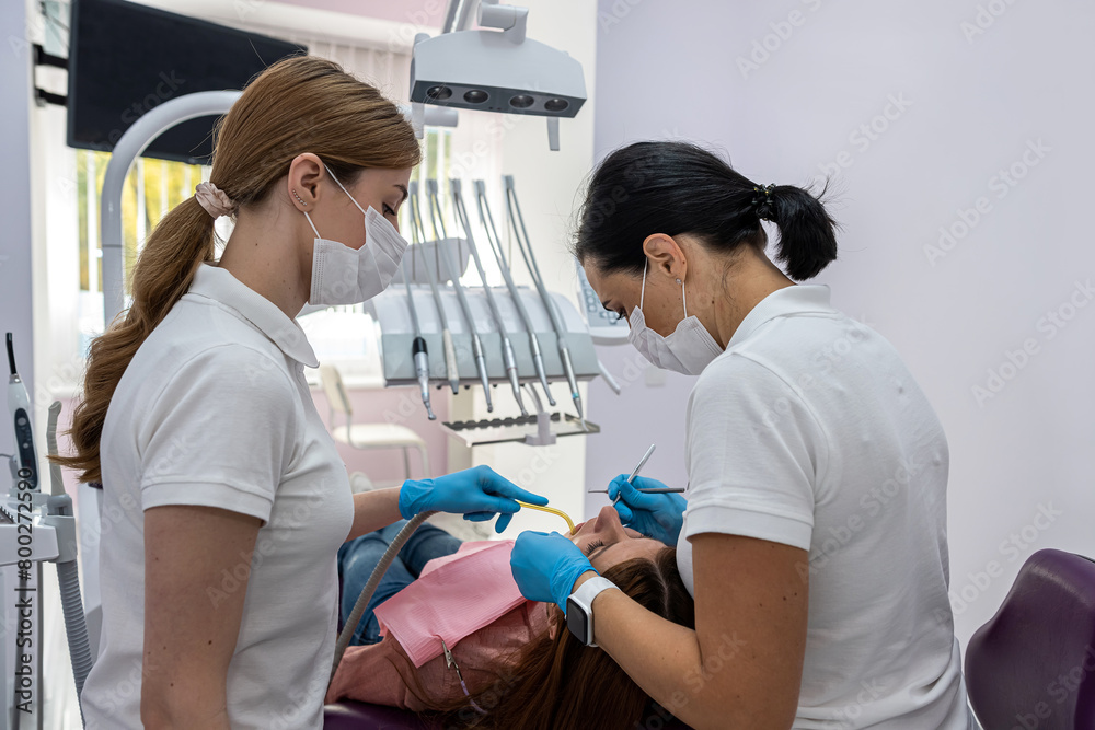 Fototapeta premium female patient being examined and treated by female dentist and an assistant in dental clinic.