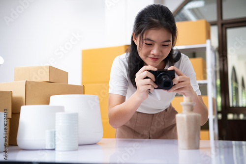 Young Asian business entrepreneur using a compact digital camera take a photo of product for upload to website online shop.