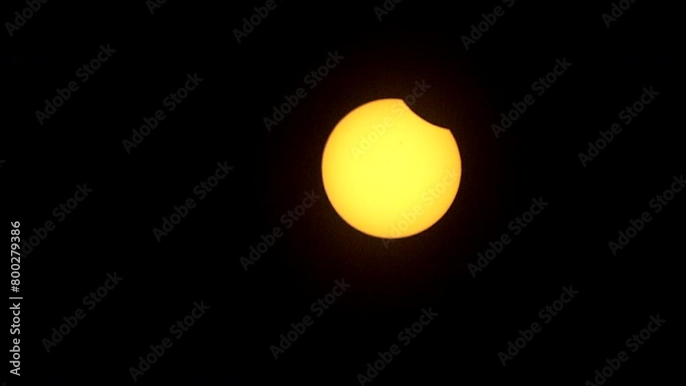 Zoom-out on solar eclipse as partial phase begins. Sunspots are visible on face of sun. Zoom-out on solar eclipse as partial phase begins. Sunspots are visible on face of sun.