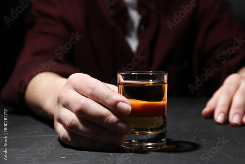 Alcohol addiction. Woman with glass of whiskey at dark textured table  selective focus