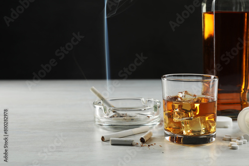 Alcohol and drug addiction. Whiskey in glass, bottle, cigarettes and pills on white table, space for text