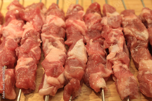 skewers with raw meat on wooden plate