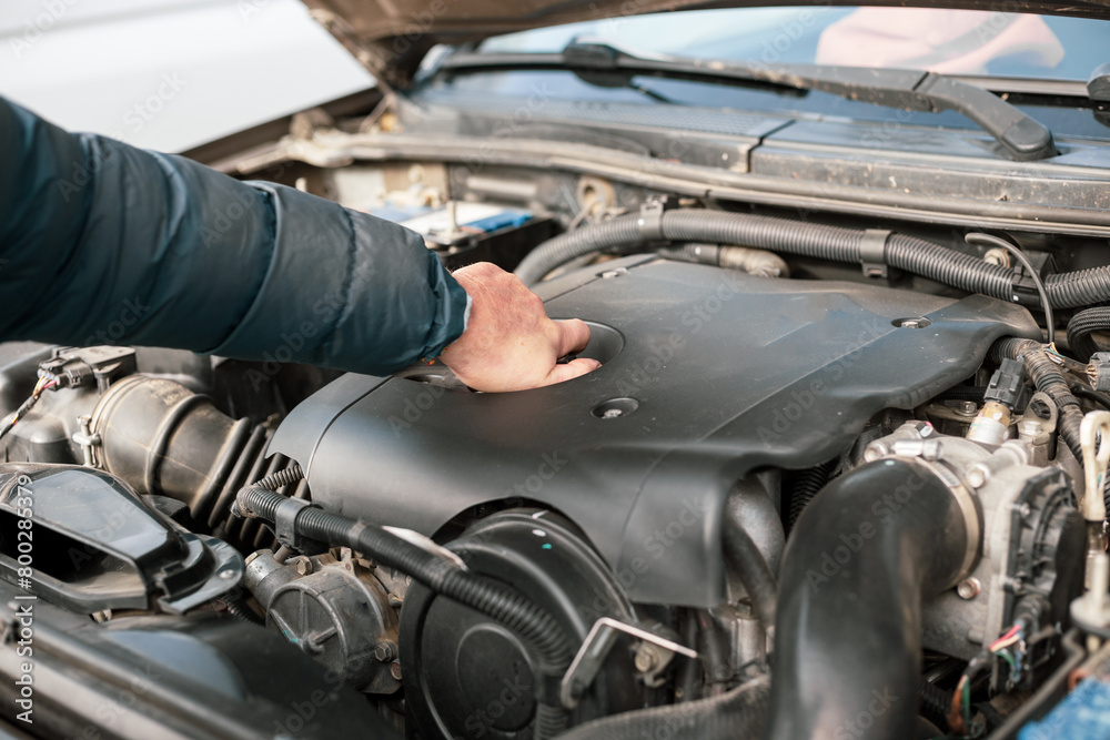A man opens the plug on a car engine to replace and top up oil, and maintain the car A man opens the plug on a car engine to replace and top up oil, and maintain the car