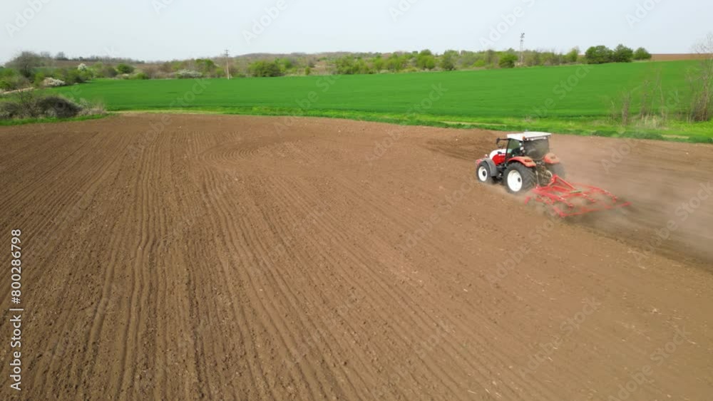 Aerial tracking drone shot of red tractor with white roof plowing and tilling fields preparing for planting. High angle footage of machinery cultivating the land for crops and harvest. Green fields!
Aerial tracking drone shot of red tractor with white roof plowing and tilling fields preparing for planting. High angle footage of machinery cultivating the land for crops and harvest. Green fields!