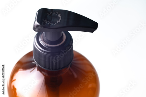 Liquid soap dispenser button, transparent plastic bottle, top view close-up macro view, isolated on white background