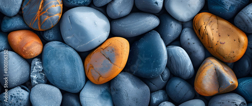 Closeup of smooth, round pebbles in various shades of blue and grey with some orange accent