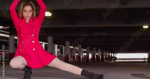 Within the bustling city's parking garage, a young girl of Hispanic heritage dons a short red dress. photo