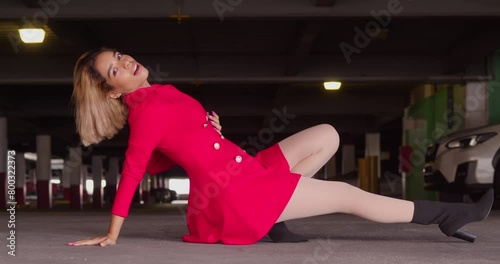 Amongst the cars and concrete of the city's parking garage, a young Hispanic girl stands out in her short red dress. photo