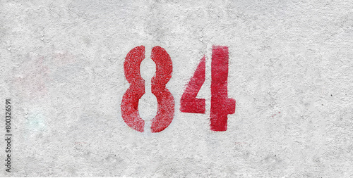 Red Number 84 on the white wall. Spray paint.