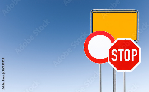 Stoppschild und Ortsschild vor blauem himmerl