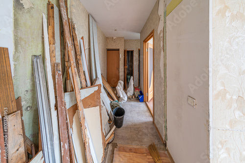 Renovation in an apartment with construction debris, gravel, broken furniture, stripped walls.