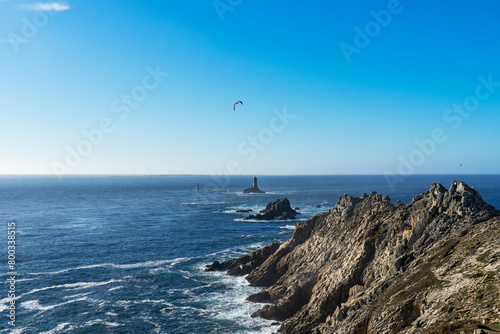 La Pointe du Raz, avec le Phare de la Vieille sur son îlot rocheux, tandis que l'île de Sein se profile à l'horizon, un paysage emblématique de la côte bretonne. photo