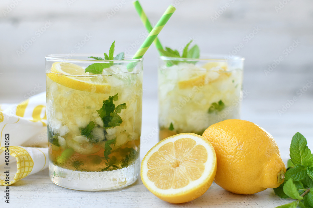 Cocktail or lemonade drink with lemon, muddled mint garnish, green straws, lemon slices Cocktail or lemonade drink with lemon, muddled mint garnish, green straws, lemon slices