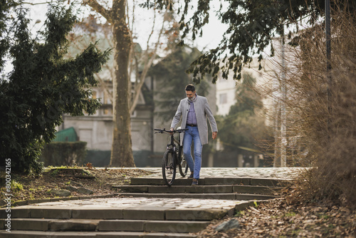 Man Walking With Bicycle Down Stone Steps in Urban Park