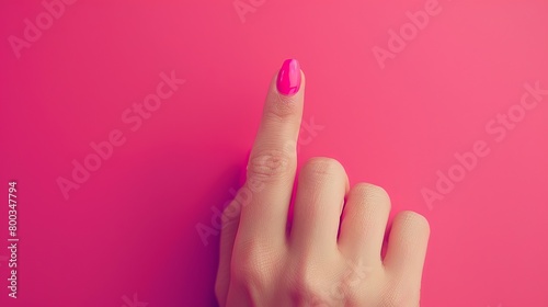  A woman's hand with pink manicures touches a single pink nail on a solid pink background