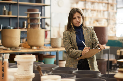 Ceramics workshop owner taking inventory in a pottery studio