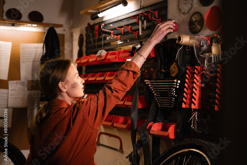 Portrait of woman mechanic in garage or workshop inspecting tools during the bike maintenance