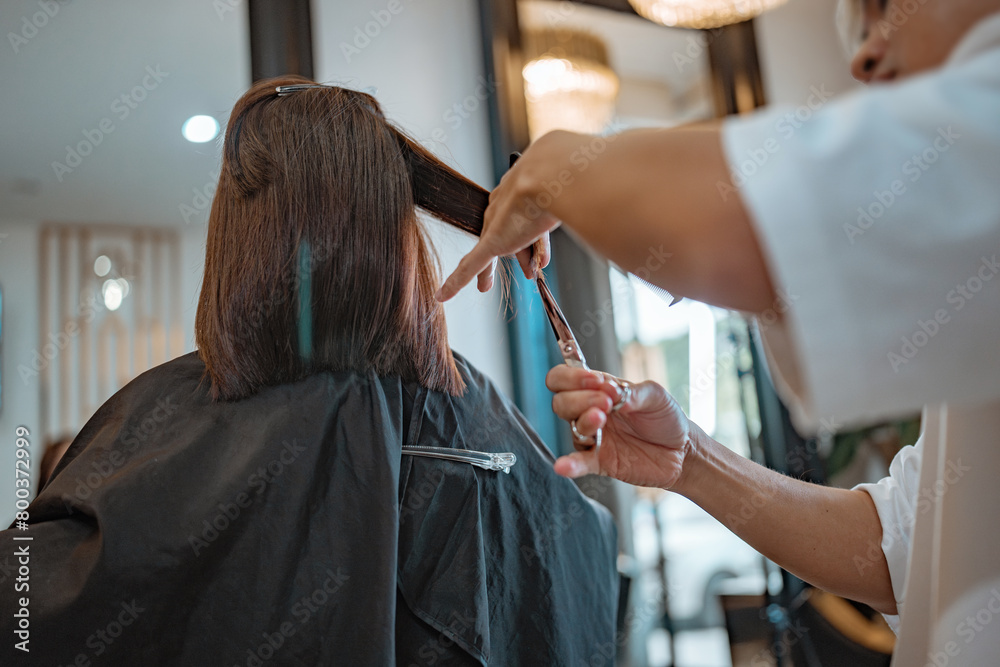 Hands of Hairdresser trimming black hair with scissors at hair beauty salon Hands of Hairdresser trimming black hair with scissors at hair beauty salon