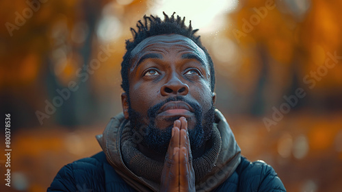 close-up of young faithful black man with hands together praying, looking up, hope, prayer
