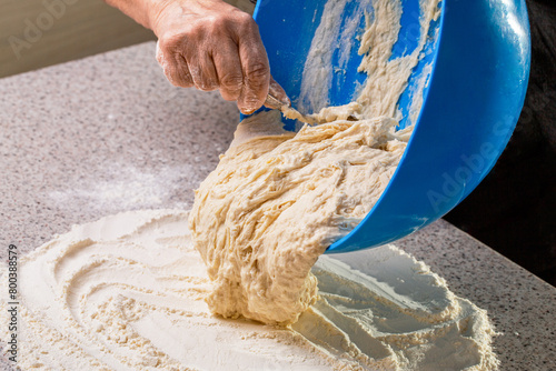 Fotografie Hand woman pours dough from a bowl onto the table