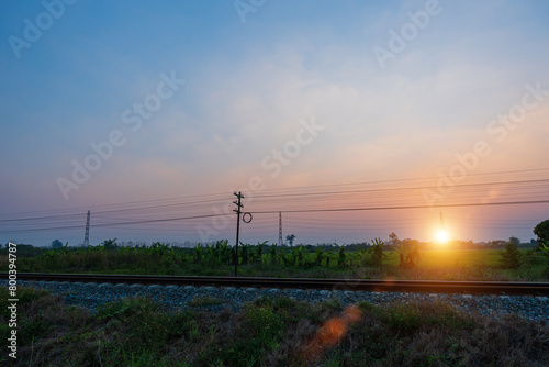 View of railway tracks in a rural scene during sunset sky.