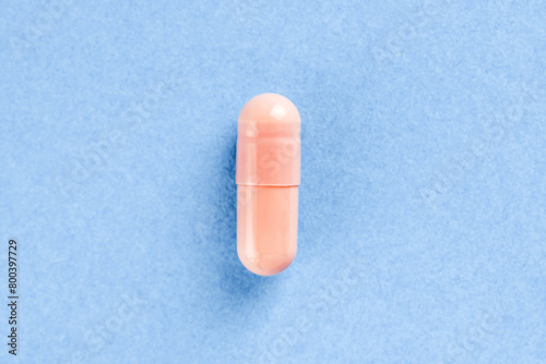 Pink two-piece hard starch capsule on blue background with copy space. Medical and Health concept.