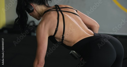 Woman lifting dumbbell at the gym for latissimus dorsi muscles photo