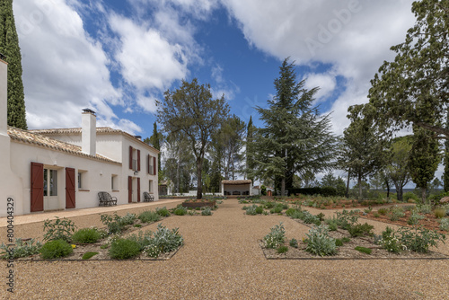 newly planted gardens with trees and a farm-style cottage to the side photo