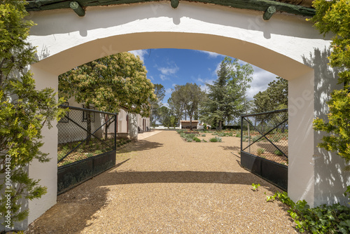 Entrance to a farm with gardens with trees, plants recently planted on the property with terracotta floors, gravel and slabs of the same material photo