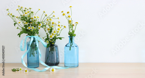 spring bouquet of daisies flowers over wooden table and white patel background photo