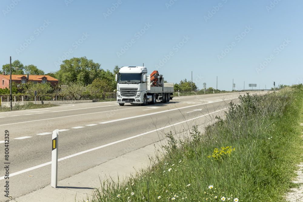 A tractor truck driving with an empty trailer with integrated crane