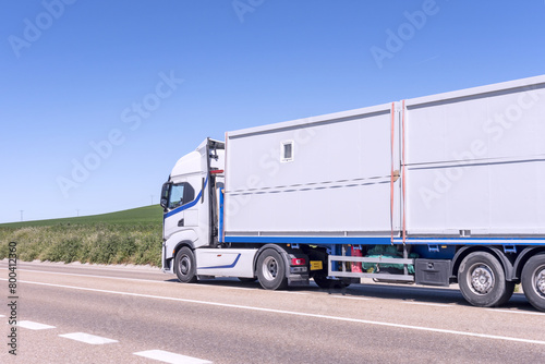 modern truck driving with a trailer with prefabricated construction sheds on a country road
