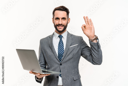 Happy office manager showing okay gesture using laptop online isolated over white background. Banker employee businessman working remotely, doin projects and startups photo