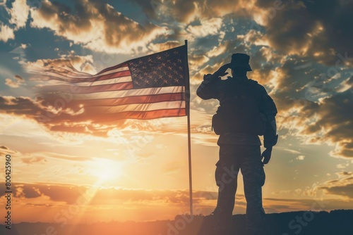 A silhouette of a soldier saluting, with the sun rising in the background and a large American flag waving in front of him.