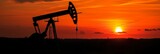 Silhouette of an oil pump against the background of fiery shades of orange sunset