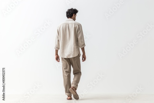 A man wearing a white shirt and khaki pants walks across a white background photo