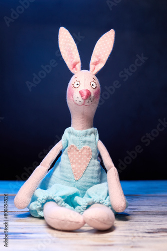 Textile handmade toy of pink bunny girl against blue background