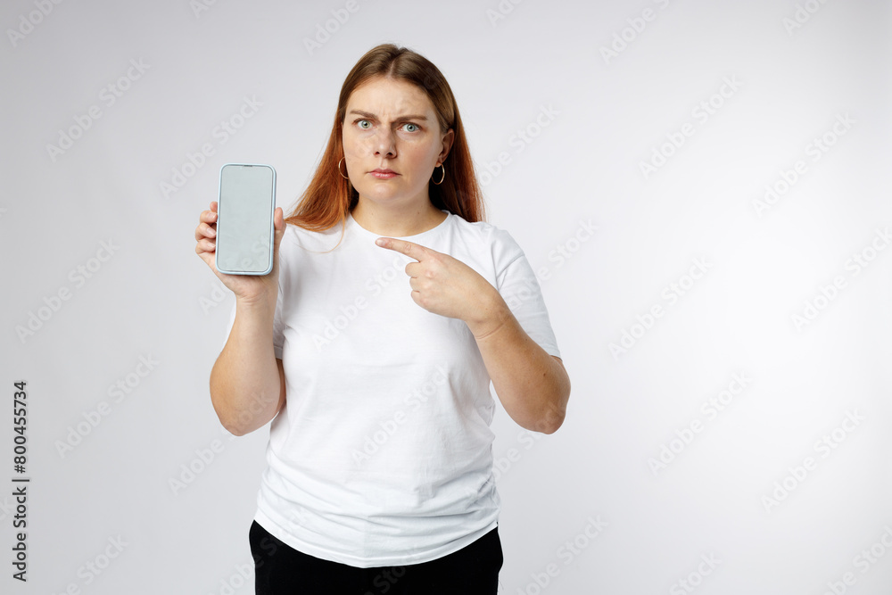Sad 30s girl showing blank screen mobile phone on white background, studio portrait. Sad 30s girl showing blank screen mobile phone on white background, studio portrait.
