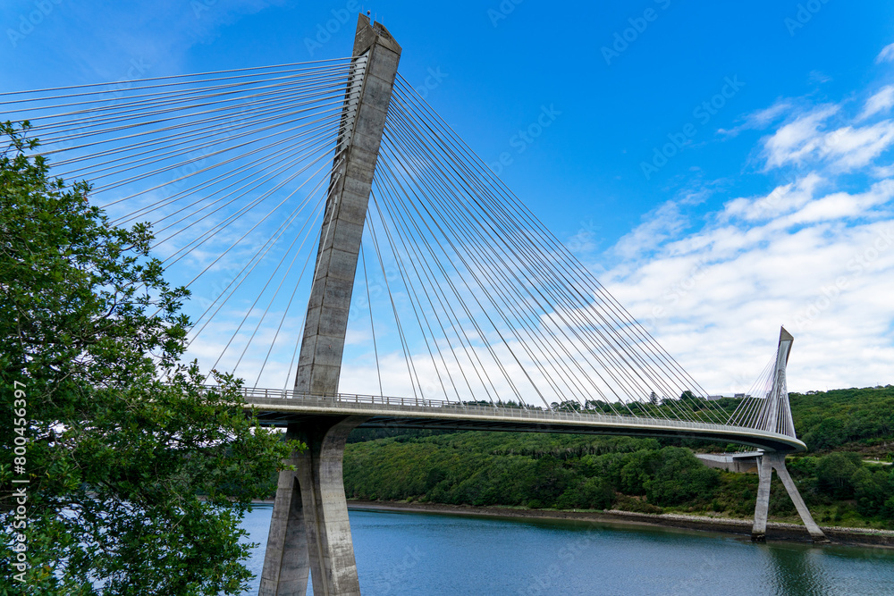 Fototapeta premium Sous un beau ciel bleu, vue sur le pont de Térénez, pont à haubans courbé au-dessus de l'Aulne, marquant l'entrée de la presqu'île de Crozon dans le Finistère, en Bretagne.
