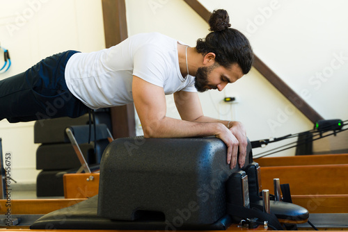 Man practicing on pilates reformer bed in studio