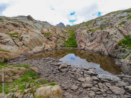 Panoramic view of small glacier pond in the Mercantour National Park in the Valley of Marvels near Tende, Provence-Alpes-Côte d'Azur Alpes-Maritimes, France. High mountain ridges in French Alps