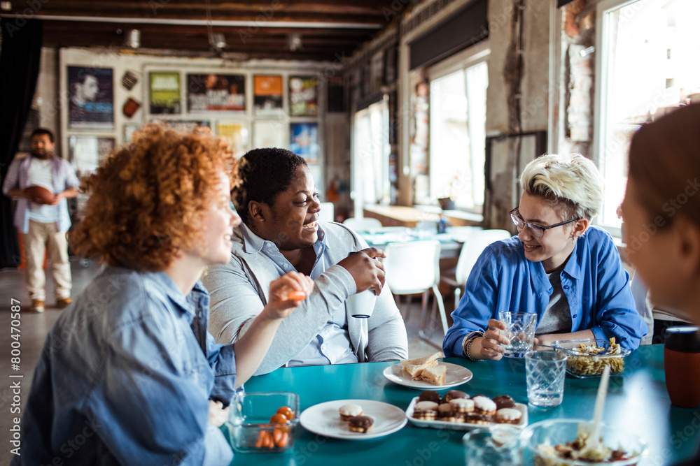 Multigenerational and diverse group of people having lunch together in a startup company office Multigenerational and diverse group of people having lunch together in a startup company office