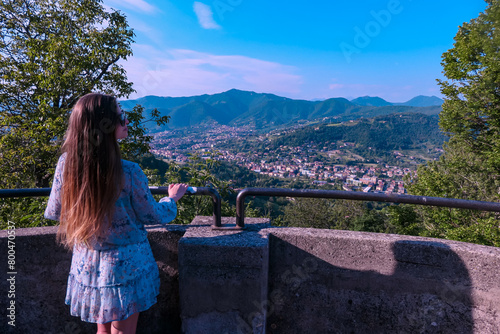 ﻿Woman on observation point with aerial view of historic medieval walled city of Bergamo seen from Città Alta (Upper Town), Lombardy, Northern Italy, Europe. Alpine landscape of Italian Alps photo