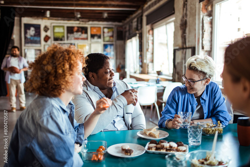 Multigenerational and diverse group of people having lunch together in a startup company office photo