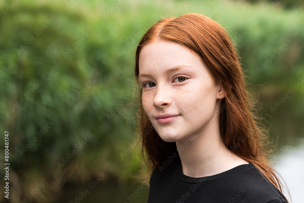 Red haired twelve year old girl with freckles posing with a nature bokeh background, Belgium