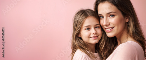 Portrait of a Caucasian mother and daughter on a pink background with copy space for text. World Mother's Day concept design for holidays, family love, motherhood celebration