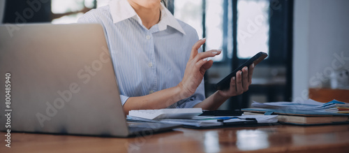 Portrait of a happy Asian businesswoman using mobile phone indoor, Asian businesswoman working in modern office.