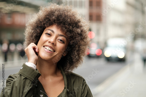 Smiling woman posing in a busy street with traffic.