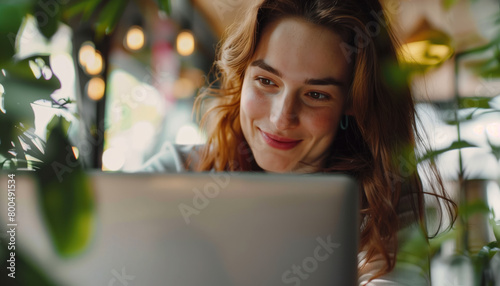 A close-up view of a happy woman looking at a laptop