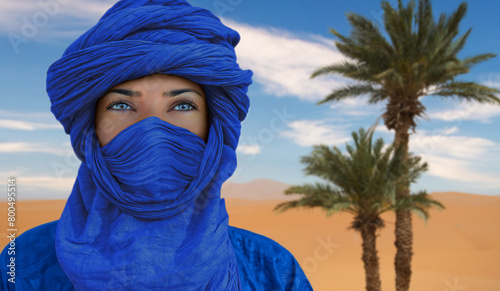 Berber woman in the Moroccan desert with palm trees in the background